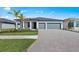 Beautiful single-story home with a two-car garage, brick driveway and a manicured lawn and tropical landscaping at 2731 Winding Creek Trl, North Port, FL 34289