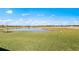 Scenic view of a pond within the community, framed by lush green grass and a clear blue sky at 2731 Winding Creek Trl, North Port, FL 34289