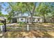 Charming home featuring a well-maintained lawn, mature trees, and a welcoming front porch with a decorative fence at 3202 W Coachman Ave, Tampa, FL 33611
