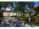 Inviting home exterior featuring a lush front yard, a carport, and charming curb appeal with trees at 3202 W Coachman Ave, Tampa, FL 33611