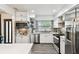 Bright and modern kitchen with white cabinetry, stainless steel appliances, stylish backsplash, and wood grain floors at 3202 W Coachman Ave, Tampa, FL 33611