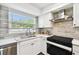 Well-lit kitchen featuring white cabinets, stainless steel appliances, stylish backsplash, and modern fixtures at 3202 W Coachman Ave, Tampa, FL 33611