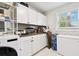 Laundry room with gray tile backsplash, additional storage and white cabinets at 3202 W Coachman Ave, Tampa, FL 33611