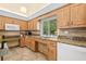 Kitchen featuring wood cabinets, granite countertops, a microwave, and a double sink beneath a window at 3810 Darston St, Palm Harbor, FL 34685