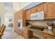 Kitchen featuring wood cabinets, granite countertops, a microwave, and a flat cooktop at 3810 Darston St, Palm Harbor, FL 34685