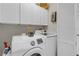 Bright laundry room with overhead cabinets, full-size washer and dryer, and a louvered door at 5634 Tanagergrove Way, Lithia, FL 33547