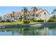 Well-maintained building exterior with lush landscaping, palm trees, pond and parking at 6131 Bahia Del Mar Blvd # 240, St Petersburg, FL 33715