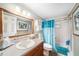 Well-lit bathroom with a wooden framed mirror, and a blue patterned shower curtain at 6821 Tierra Verde St, Port Richey, FL 34668