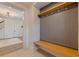 View of the mudroom which includes a gray accent wall with a wooden bench and coat hooks, and designer-tile flooring at 7120 3Rd N Ave, St Petersburg, FL 33710