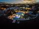 Stunning aerial view of a waterfront property with an in-ground pool and private dock, surrounded by water and city lights at 744 Spanish Main Dr, Apollo Beach, FL 33572