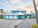 Stunning waterfront home featuring a metal roof, turquoise paint, and a three-car garage at 744 Spanish Main Dr, Apollo Beach, FL 33572