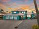 Stunning turquoise waterfront home with a metal roof, three-car garage, and well-manicured landscaping at 744 Spanish Main Dr, Apollo Beach, FL 33572