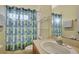 Well-lit bathroom featuring a shower with a blue and green patterned curtain, a sink, and a rack at 7740 Blue Spring Dr, Land O Lakes, FL 34637