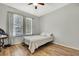 Bright bedroom with hardwood floors, a ceiling fan, two windows, and a simple bed frame at 7740 Blue Spring Dr, Land O Lakes, FL 34637