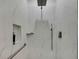 A stylish shower featuring gray fixtures, marble tile, and a built-in shelf at 7740 Blue Spring Dr, Land O Lakes, FL 34637
