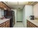 Galley kitchen featuring wood cabinets, tiled floors and adjacent pantry storage at 9910 Eagles Point Cir # 3, Port Richey, FL 34668