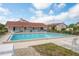 Community pool next to a clubhouse offers lounge chairs and tables under a sunny blue sky at 9910 Eagles Point Cir # 3, Port Richey, FL 34668