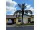 Charming yellow home featuring a well-manicured lawn, large palm tree, and an attached garage at 1012 Warwick Ct, Sun City Center, FL 33573