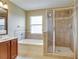 Bathroom features a tub, glass shower and a wooden vanity with tan tile at 11308 Callaway Pond Dr, Riverview, FL 33579
