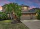 Two-story home features a three-car garage, and lush landscaping with several palm trees at 11308 Callaway Pond Dr, Riverview, FL 33579