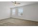Cozy bedroom featuring carpet flooring, two windows, and a ceiling fan at 12017 Grand Kempston Dr, Gibsonton, FL 33534