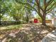 Large backyard featuring mature trees, a wooden fence, and a small red shed at 13556 Lake Magdalene Dr, Tampa, FL 33613