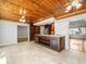 Open kitchen area with a large island, custom wood ceiling, and adjoining living space at 13556 Lake Magdalene Dr, Tampa, FL 33613
