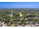 Aerial view showing homes with mature trees, streets, and tranquil pond and city in the distance, and arrow indicator at 1536 Alamo Ln, Dunedin, FL 34698