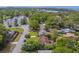 Aerial neighborhood view with winding streets, mature trees and greenery, and pond in the distance at 1536 Alamo Ln, Dunedin, FL 34698