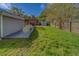 View of a backyard with a spacious grassy area, wooden pergola, surfboard, and storage shed at 1536 Alamo Ln, Dunedin, FL 34698