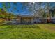 View of a backyard with a spacious grassy area, wooden pergola, and surfboard at 1536 Alamo Ln, Dunedin, FL 34698