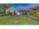 Quaint home with a well-maintained lawn, established landscaping, and a charming brick path at 1536 Alamo Ln, Dunedin, FL 34698