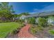 Charming home with attractive landscaping, mature trees, and a welcoming brick walkway at 1536 Alamo Ln, Dunedin, FL 34698
