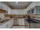 Well-lit kitchen features white cabinets, stainless steel appliances, granite counters, and tiled backsplash at 1536 Alamo Ln, Dunedin, FL 34698