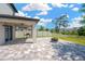 A patio with a ceiling fan, brick paved surface with an outdoor kitchen overlooking the green backyard at 19592 Breynia Dr, Lutz, FL 33558