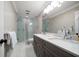 Contemporary bathroom featuring a double sink vanity, glass-enclosed shower, and neutral color palette at 21 Pelican Pl, Belleair, FL 33756