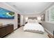 Neutral bedroom featuring a TV, white bedding, an area rug and light-filled window at 21 Pelican Pl, Belleair, FL 33756