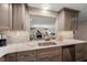 Well-lit kitchen with stainless steel sink and appliances, quartz countertops, and a view to the living room at 21 Pelican Pl, Belleair, FL 33756