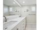 Bright bathroom featuring a double sink vanity, large mirror, and white tile flooring at 2216 El De Oro Dr, Clearwater, FL 33764