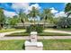 Landscaped front yard with tropical plants, palm trees, circular driveway, and charming mailbox at 2216 El De Oro Dr, Clearwater, FL 33764