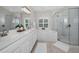 Bright bathroom boasts dual sinks, a large tub, and a glass-enclosed shower for a spa-like experience at 3385 Clarine E Way, Dunedin, FL 34698