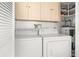 Functional laundry room with washer, dryer, upper cabinets, and water heater at 4022 Lighthouse Way, New Port Richey, FL 34652