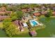Aerial view of community pool, dock, and clubhouse with tropical landscaping, solar panels and lake views at 4424 Pelorus Dr, New Port Richey, FL 34652