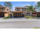 Two-story condo building with a covered carport area for parking vehicles with grass, trees, and blue skies overhead at 4424 Pelorus Dr, New Port Richey, FL 34652