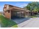 Two-story condo building with a covered carport area for parking vehicles with grass, trees, and blue skies overhead at 4424 Pelorus Dr, New Port Richey, FL 34652