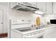 Well-lit kitchen features a white stove, range hood, and sink, offering a functional cooking space at 4424 Pelorus Dr, New Port Richey, FL 34652