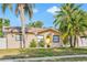Charming single-story home with a bright yellow front door, surrounded by lush tropical landscaping and palm trees at 715 Charlotte Ave, Tarpon Springs, FL 34689