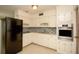 Well-lit kitchen with white cabinetry, modern appliances, mosaic backsplash and neutral flooring at 721 75Th N Ave, St Petersburg, FL 33702