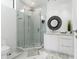 Bright bathroom features a glass-enclosed shower, modern vanity, and stylish round mirror at 7608 Antilla St, Tampa, FL 33625