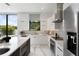 Bright, modern kitchen with white cabinets, marble floors, stainless steel appliances, and large window overlooking the yard at 7608 Antilla St, Tampa, FL 33625